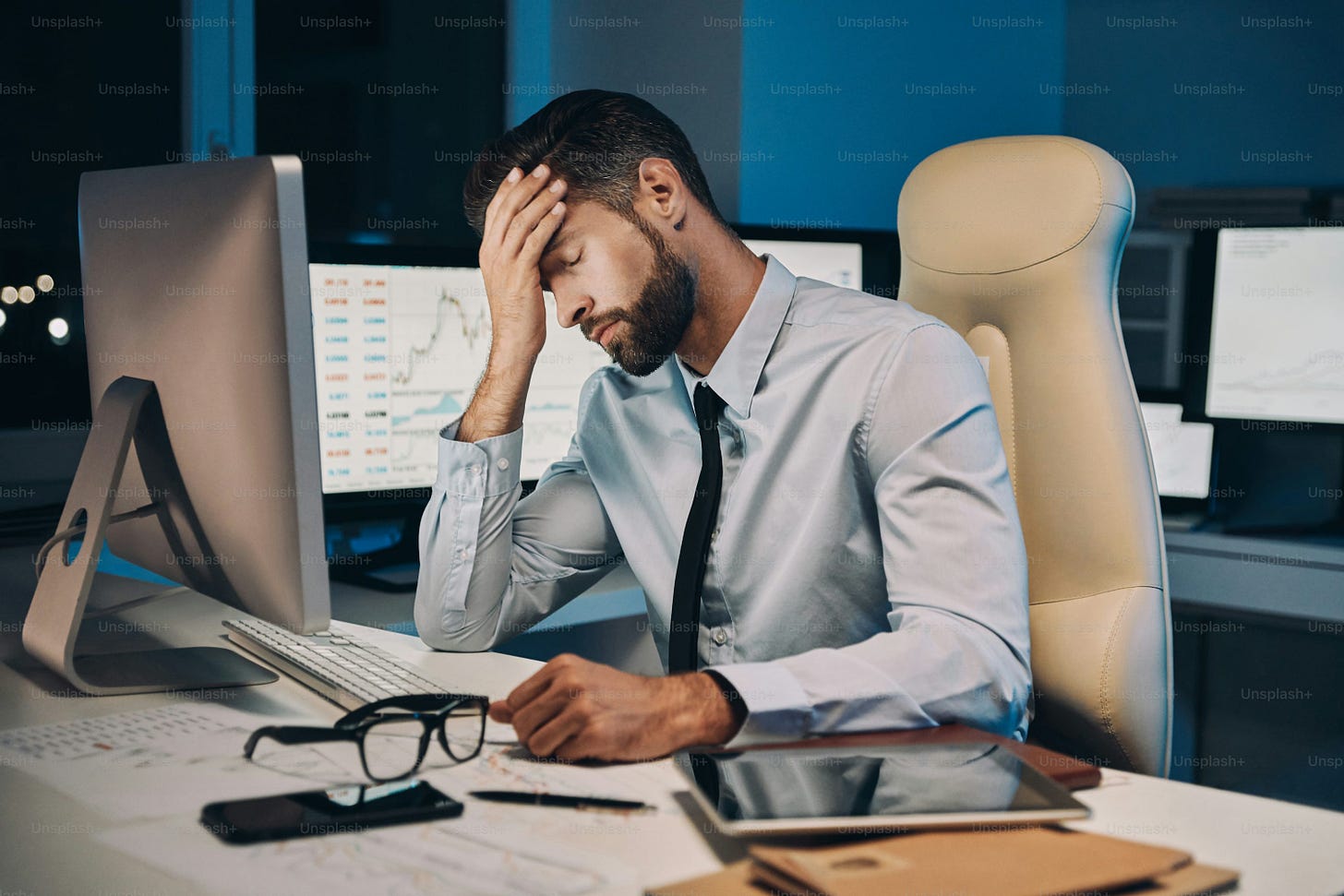 Frustrated young man in shirt and tie having headache while staying late in the office Frustrated young man in shirt and tie having headache while staying late in the office