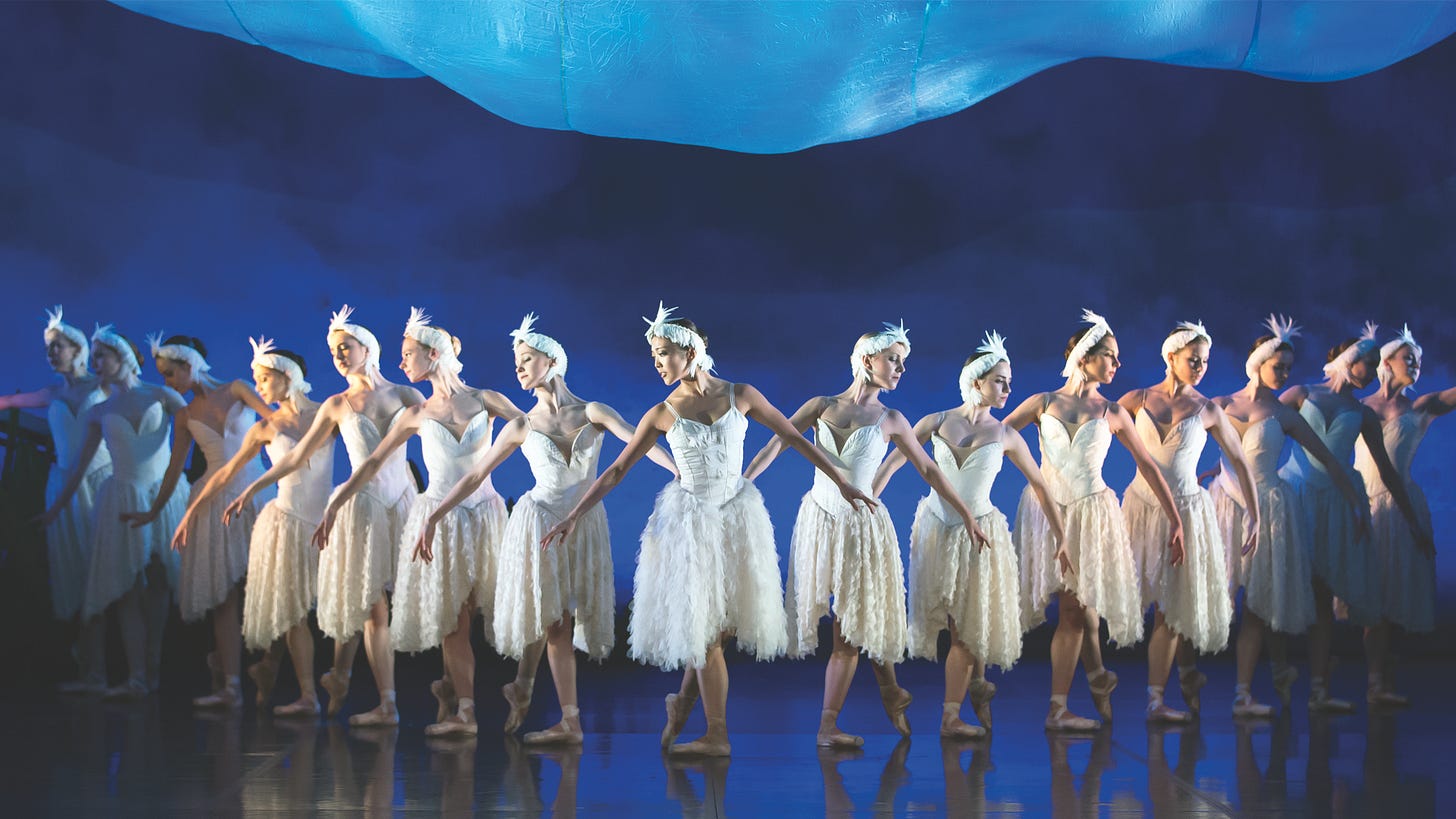 Iconic image of a Swan Lake corps de ballet lined up against a background of blue hills.