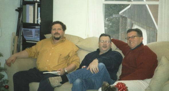 Photo of three men seated on a couch.