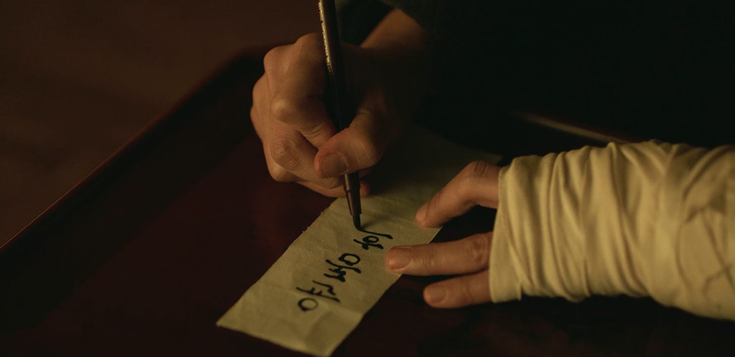 Choi Mu-jin the temple, writing Yoon Dong-hoon's name on a piece of parchment, episode six of My Name (2021)