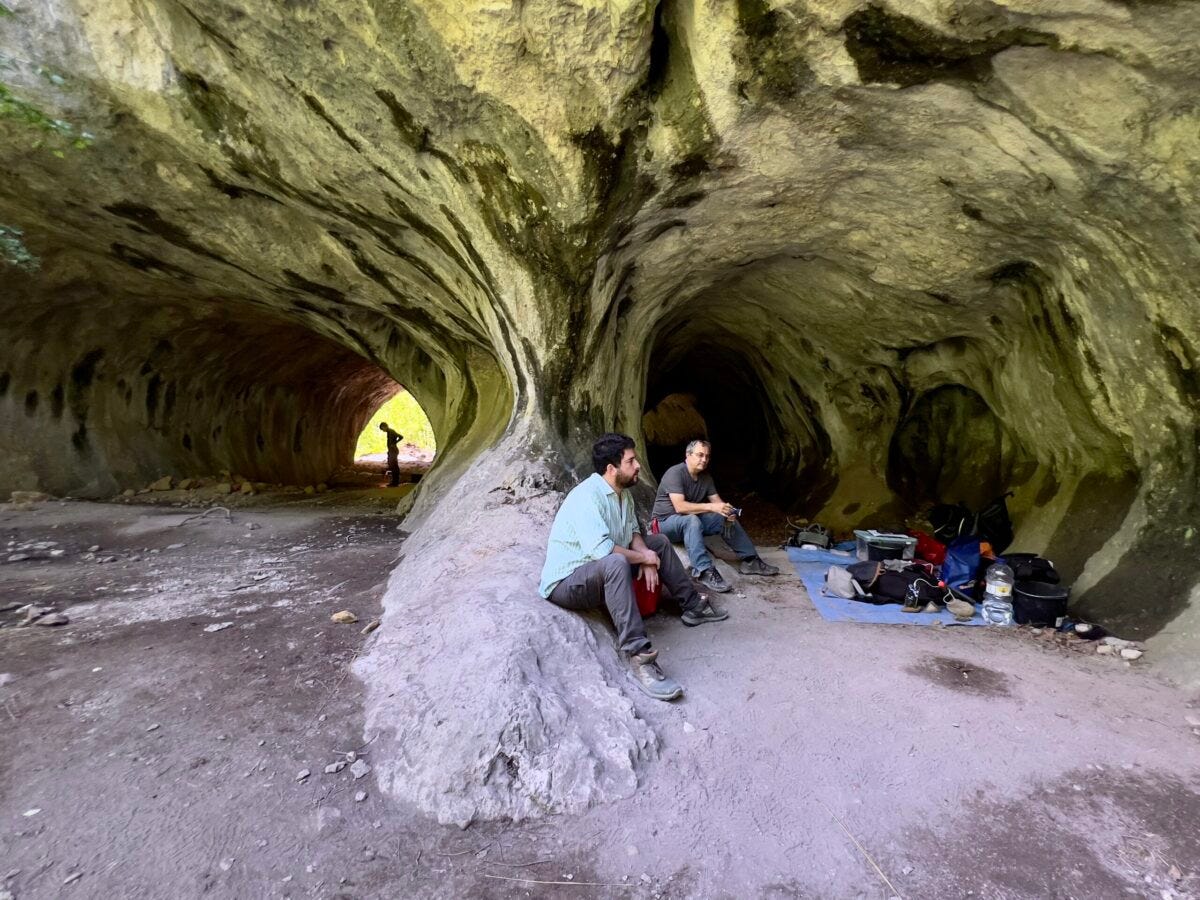 Os pesquisadores André Strauss e Clovis Monteiro, da USP, descansam em uma das entradas da caverna Tatarului, que possui dois túneis paralelos, parecidos com traqueias humanas. No fundo do túnel à esquerda aparece a silhueta do mestrando Victor Nery, aluno do MAE USP - Foto: Herton Escobar / USP Imagens