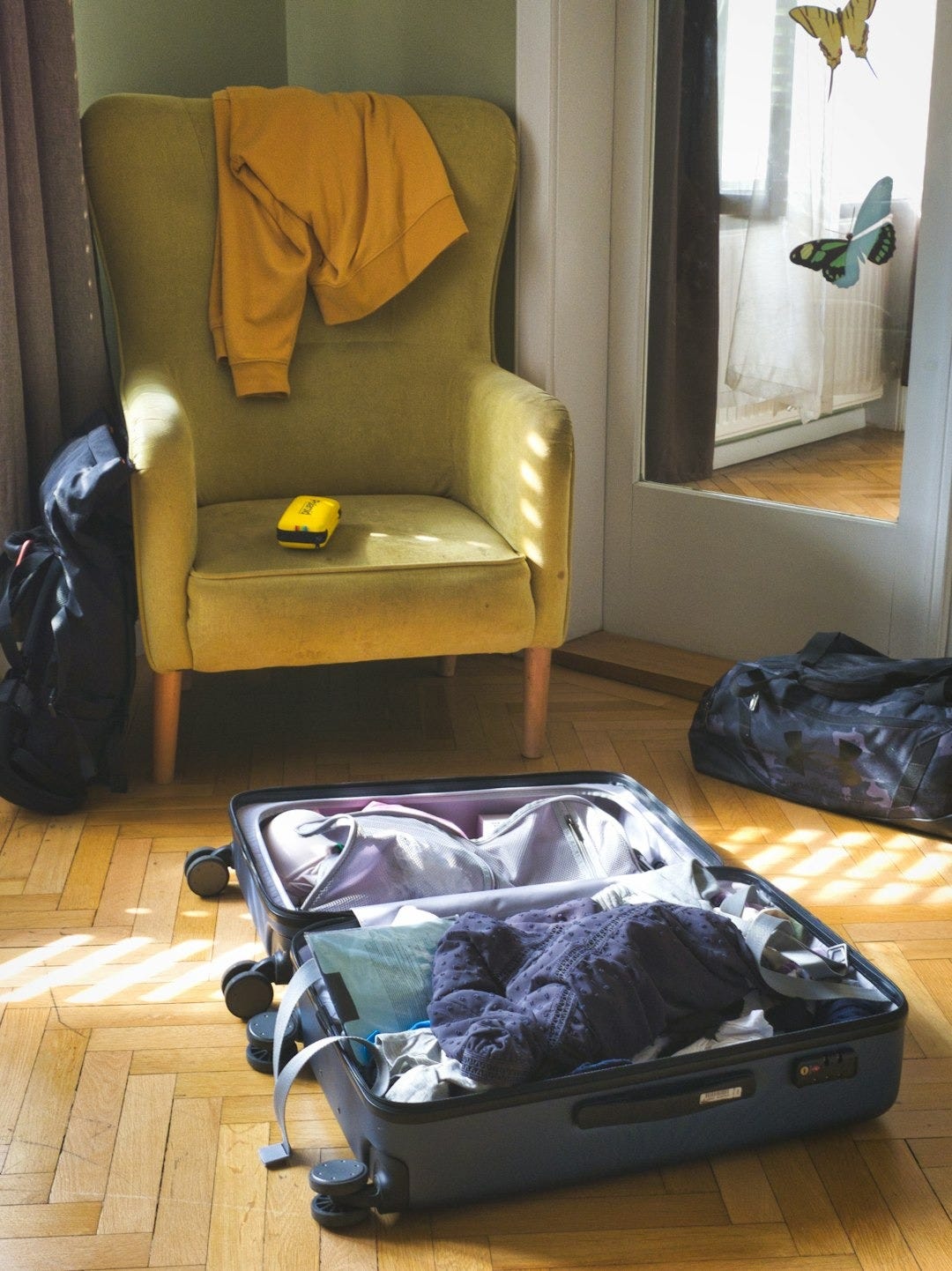 Open suitcase with clothes and armchair in a room Open suitcase with clothes and armchair in a room