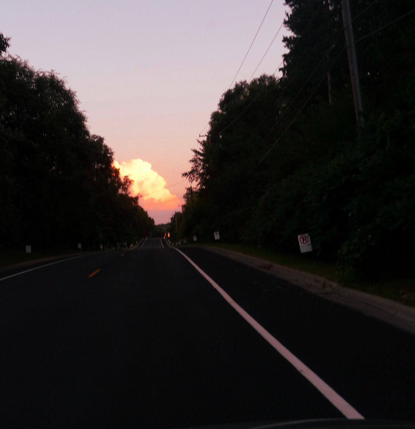 A pink cloud peaks out over the road.