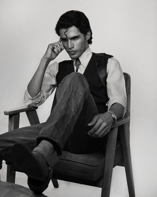 Free Black and white portrait of a man in deep thought sitting on a chair. Stock Photo