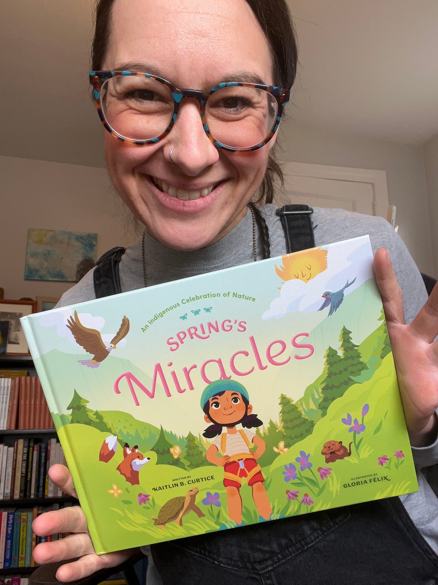 kaitlin holds a copy of spring's miracles in her hand while sitting in her office