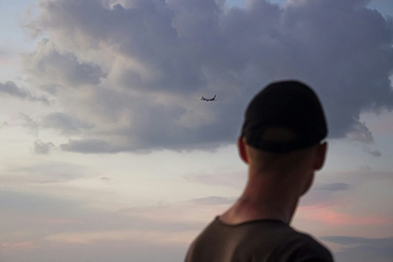 A man watches a departing airplane. A man watches a departing airplane.