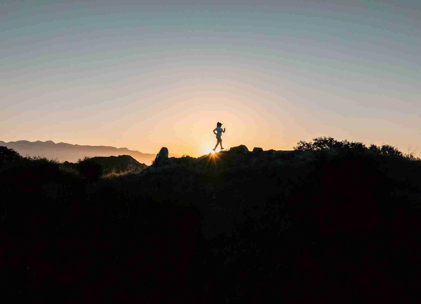 Silhouette of a runner on a ridge at sunset Silhouette of a runner on a ridge at sunset