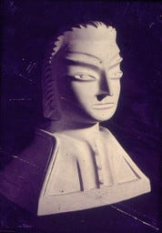 A imagem 1 exibe uma escultura em busto de gesso ou material similar, que representa um guerreiro mitológico, uma obra do artista brasileiro Lúcio Noeman. A iluminação dramática com sombras profundas, destaca as características faciais angulares e expressivas da peça. O busto possui uma expressão séria e intensa, com sobrancelhas proeminentes e olhos fixos. O trabalho é notável pela sua qualidade artística e detalhes precisos, como a textura na parte de trás da cabeça, sugerindo um penteado ou adorno.  A imagem 2 A imagem mostra uma escultura de rosto em um material branco e áspero, que parece ser gesso ou pedra.  O rosto possui uma expressão contorcida, que transmite angústia, choque ou sofrimento, com olhos vazios e a boca aberta em um formato irregular. A textura da obra é rugosa e não polida, e a forma é aproximadamente retangular ou em bloco.