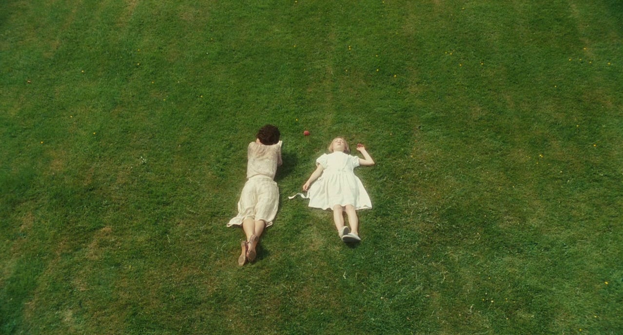 A still from the film Atonement: two girls laying on the grass