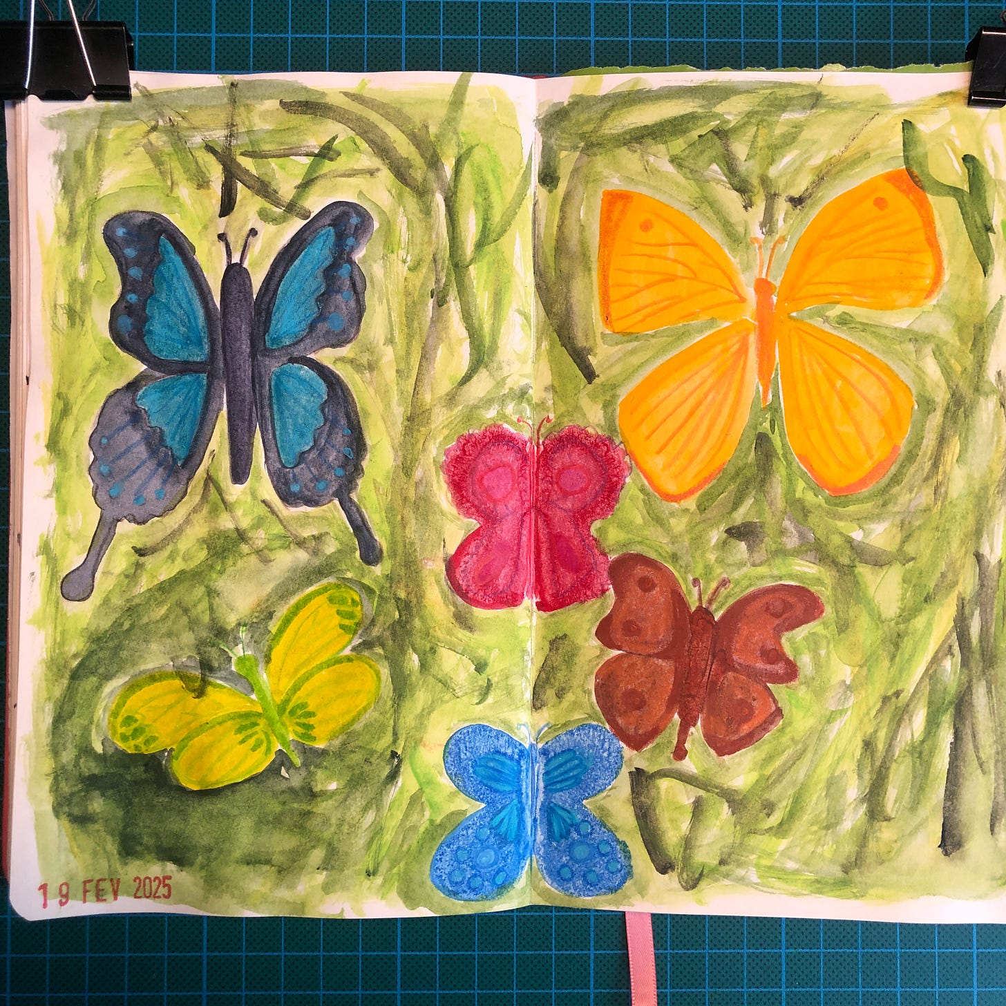 Photos de la double-page de mon sketchbook où l'on voit des papillons peints : un noir et bleu, un jaune et orange, un jaune et vert, un rose, un bleu, un marron. Un fond de plusieurs nuances de verts a été peint autour des papillons.