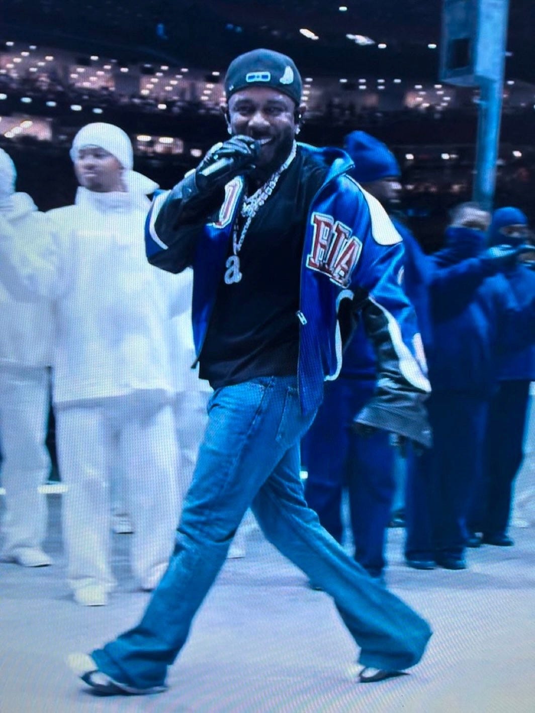 A photo of Kendrick Lamar at the the Super Bowl halftime show looking directly in the camera and smiling A photo of Kendrick Lamar at the the Super Bowl halftime show looking directly in the camera and smiling