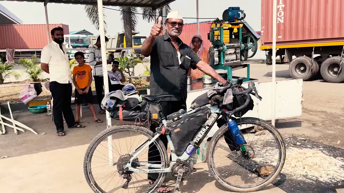 Un indien levant le pouce devant le velo du voyageur