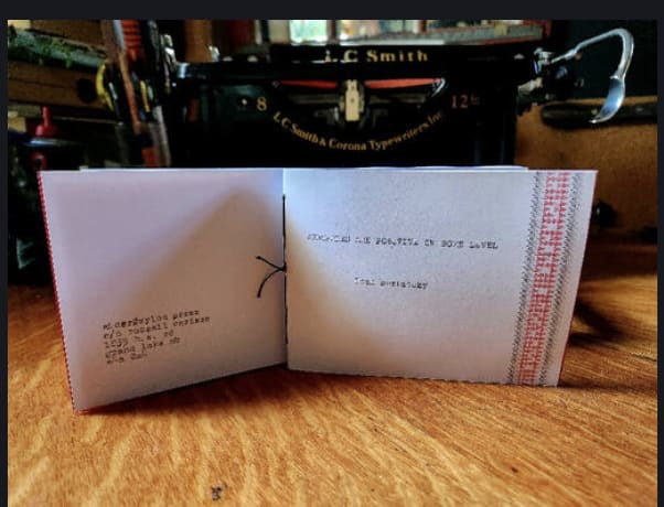 picture of chapbook open on edge on table; bound with ties! fancy!
