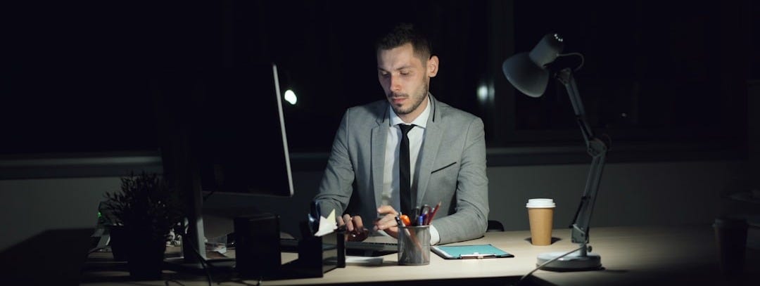 Man working late at his desk with coffee.