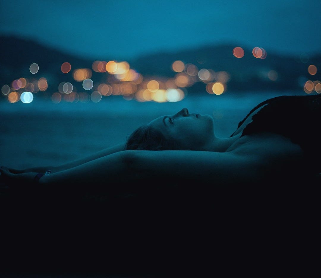 A woman is laying down in the dark