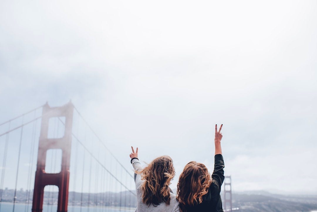 two women making peace sign near the Golden Gate bridge two women making peace sign near the Golden Gate bridge