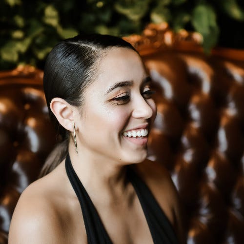 Photo of Nicolle Lopez, Social Media Manager at Amtrak. She's wearing a black top and is smiling and looking off to the side of the frame.