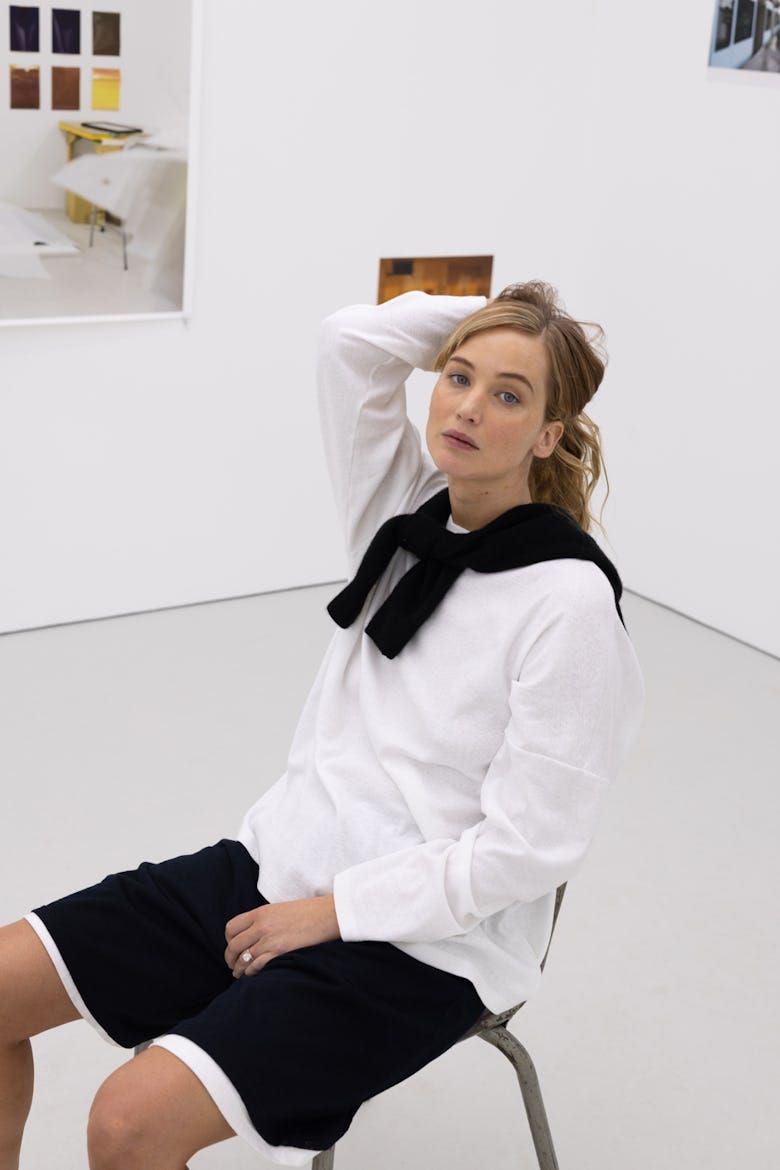 Jennifer Lawrence seated in white top and black shorts