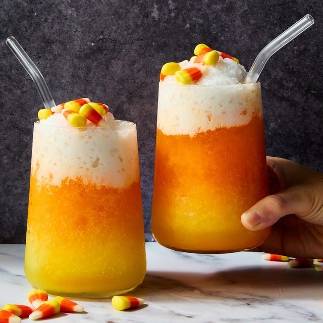layered cocktail with yellow, orange, and white layers topped with candy corn, Picture layered cocktail with yellow, orange, and white layers topped with candy corn, Picture