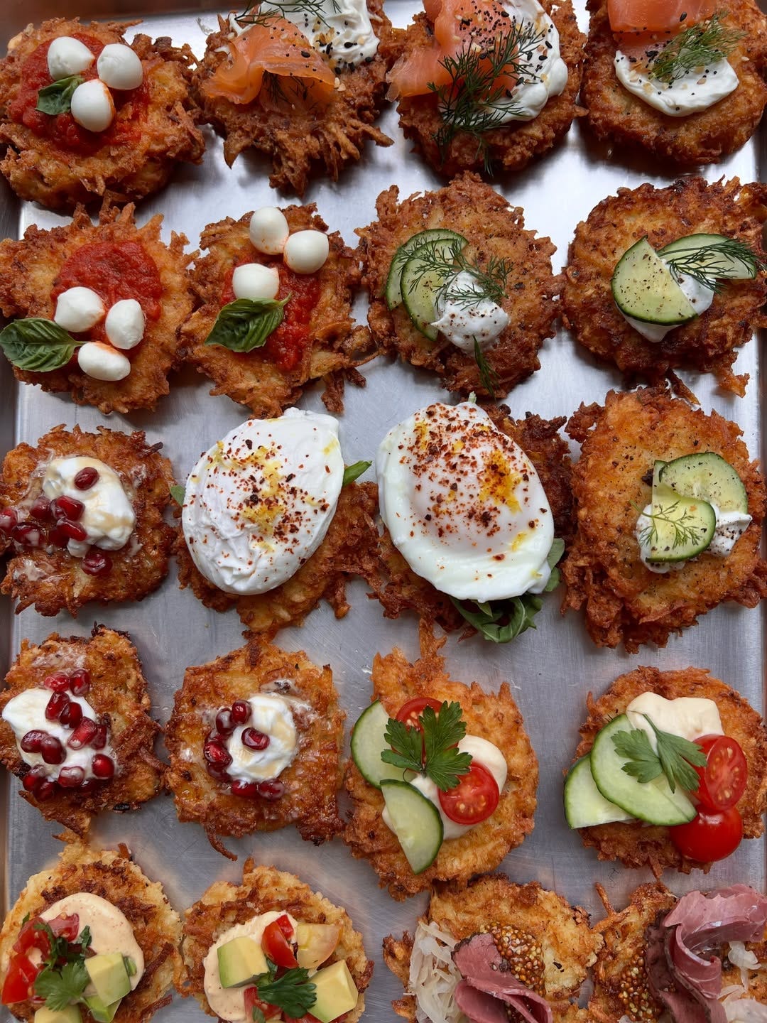 a silver sheet pan with variety of latke and toppings a silver sheet pan with variety of latke and toppings