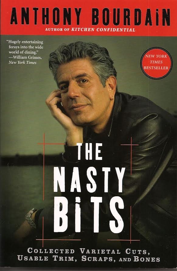 Pictured is a middle-aged Anthony Bourdain posing with his hand cupping his cheek as he stares into the camera. He is wearing a hoop earring, leather jacket, and plain jane watch. Above him is his name written in black in front of a red border and in front of him is the title page “The Nasty Bits” in a warehouse-style bold font in white.