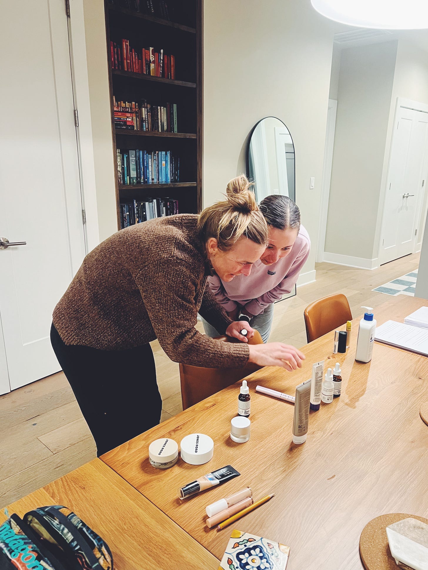 Jenny and Danielle looking at makeup on the dining room table