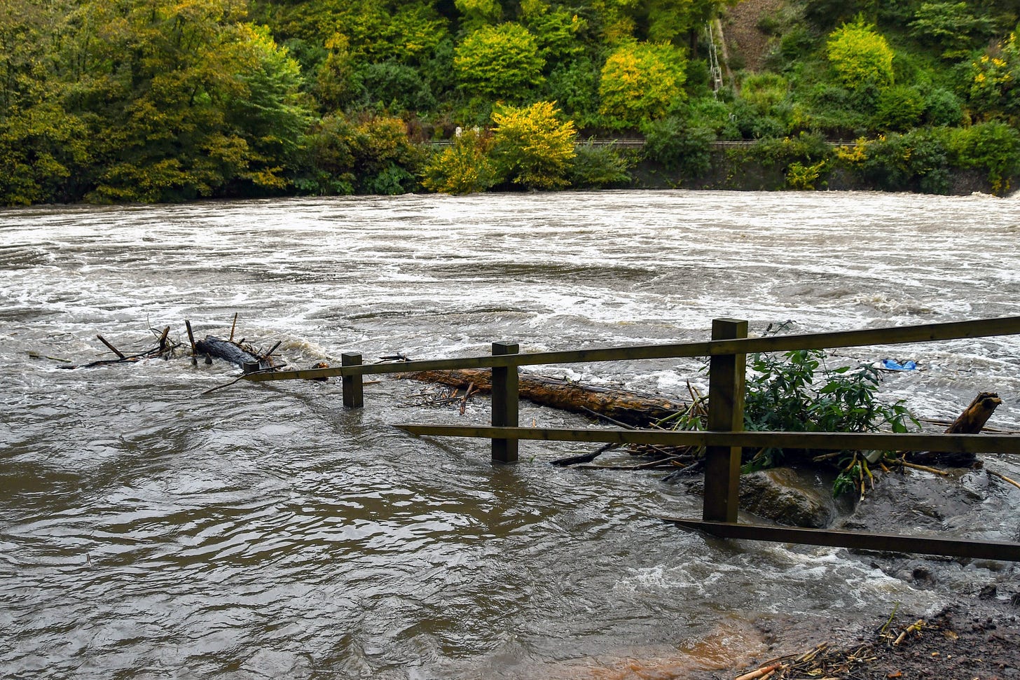 Floodwaters moving over and through a fence
