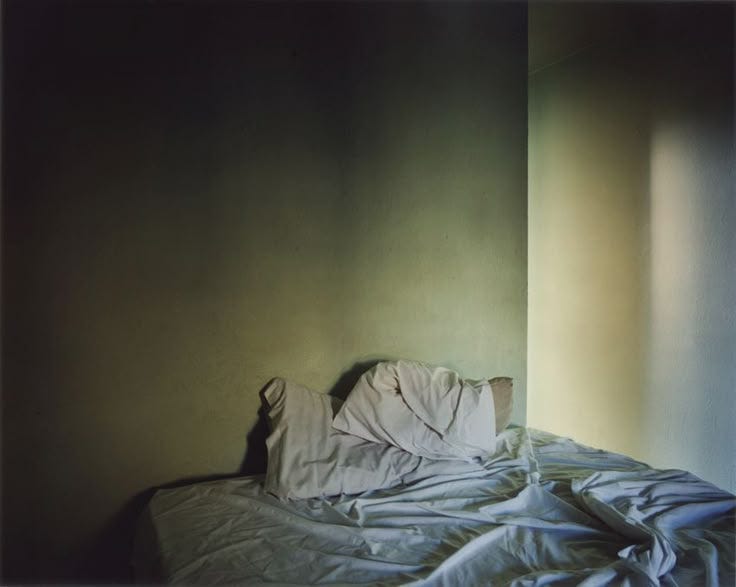 This may contain: an unmade bed with white sheets and blankets on it in a room that has green walls