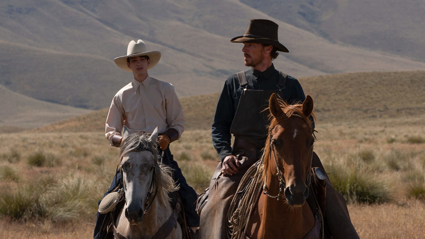 The Power of the Dog | Still features Benedict Cumberbatch as Phil Burbank on horseback with Kodi Smit-McPhee as Peter Gordon behind him.