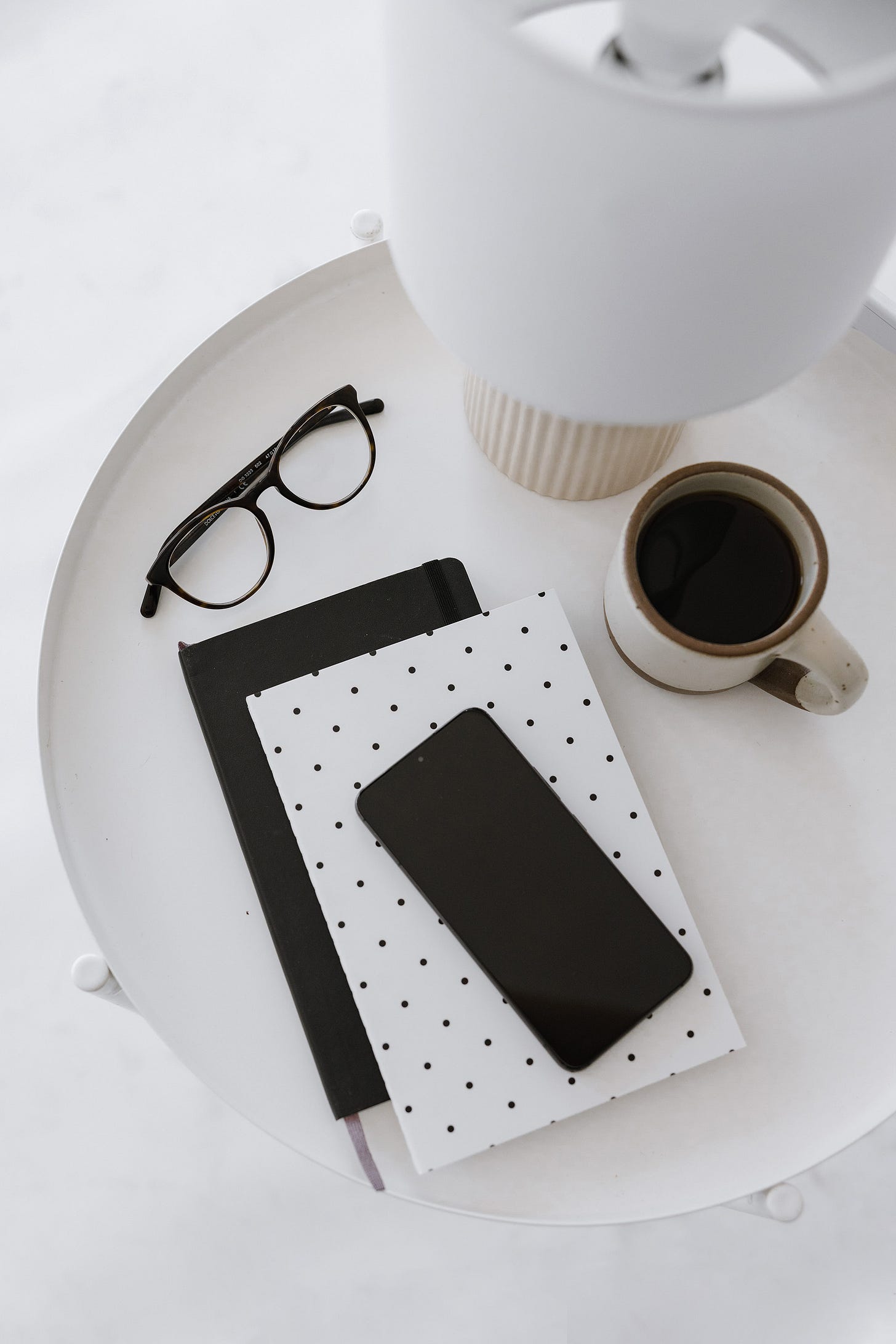 flat lay of coffee table with coffee mug, glasses, and notebooks