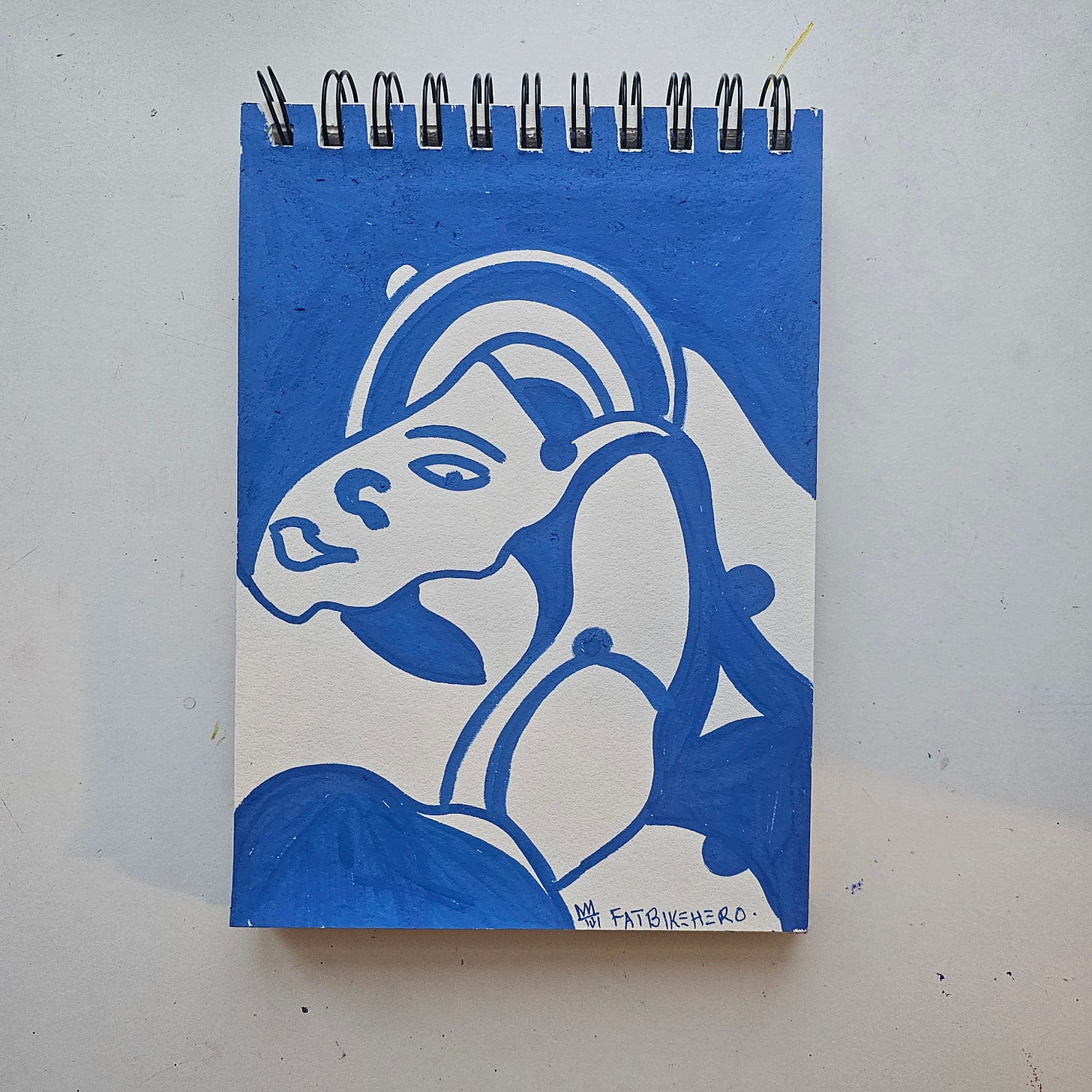 A striking, high-contrast portrait painting by FatbikeHero (b. 1983) rendered in deep cobalt blue acrylic marker on white sketchbook paper. The image depicts a stylized female profile with a sculptural, curved headdress, utilizing negative space to define the facial features in a manner reminiscent of Matisse's cut-outs or Cubist abstraction. The blue application is solid and opaque.