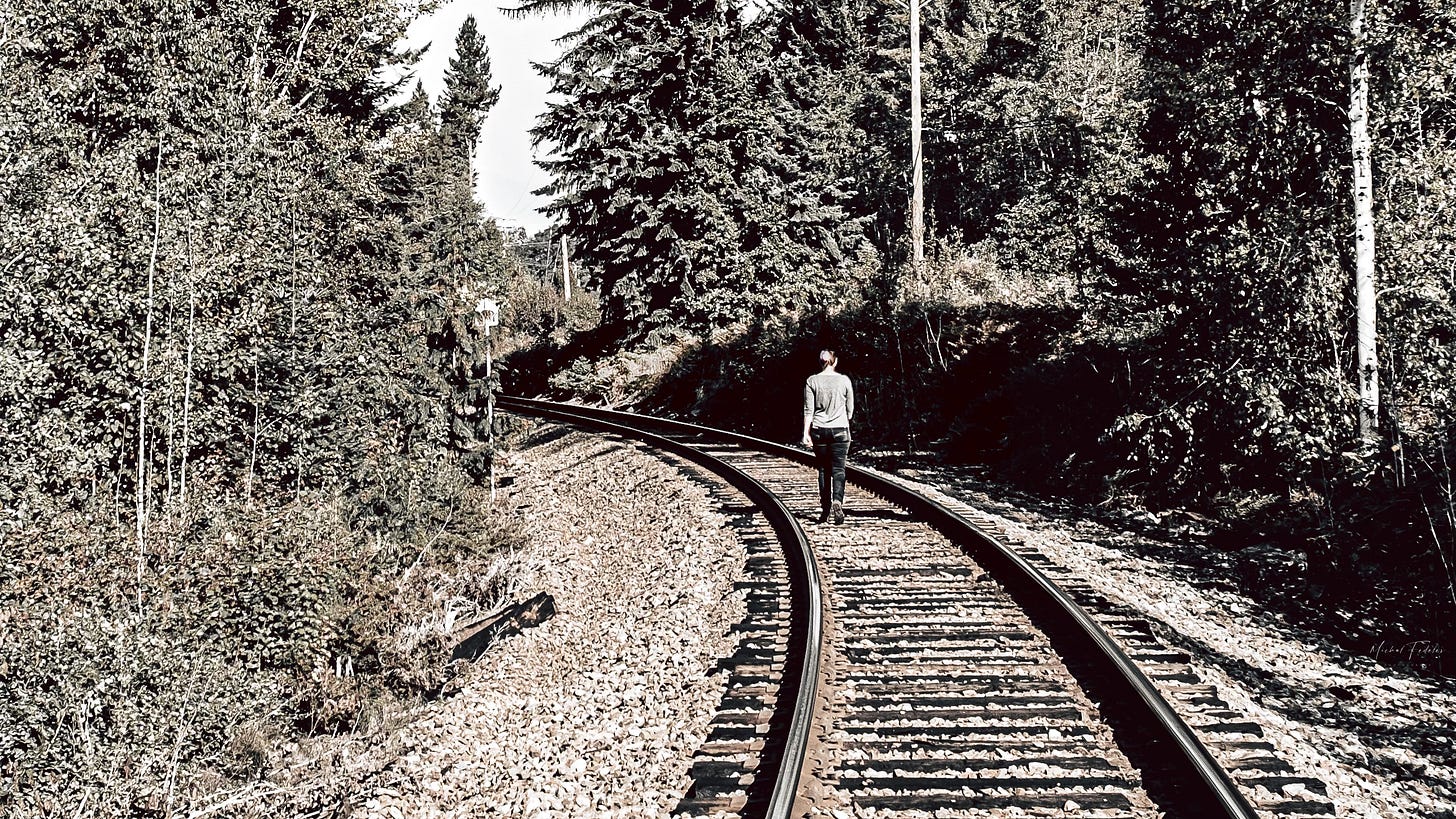 A person walking into the distance along railway tracks. A person walking into the distance along railway tracks.