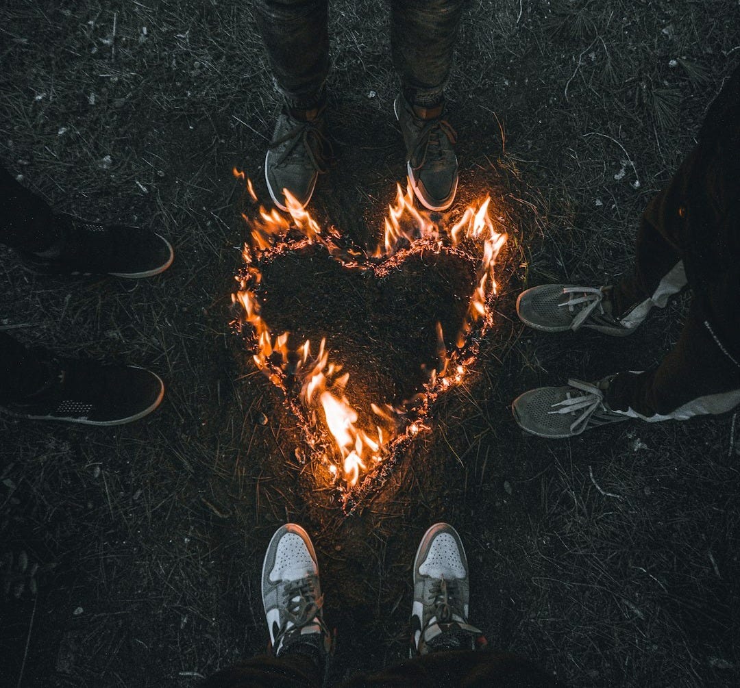 a person standing in front of a heart made of fire