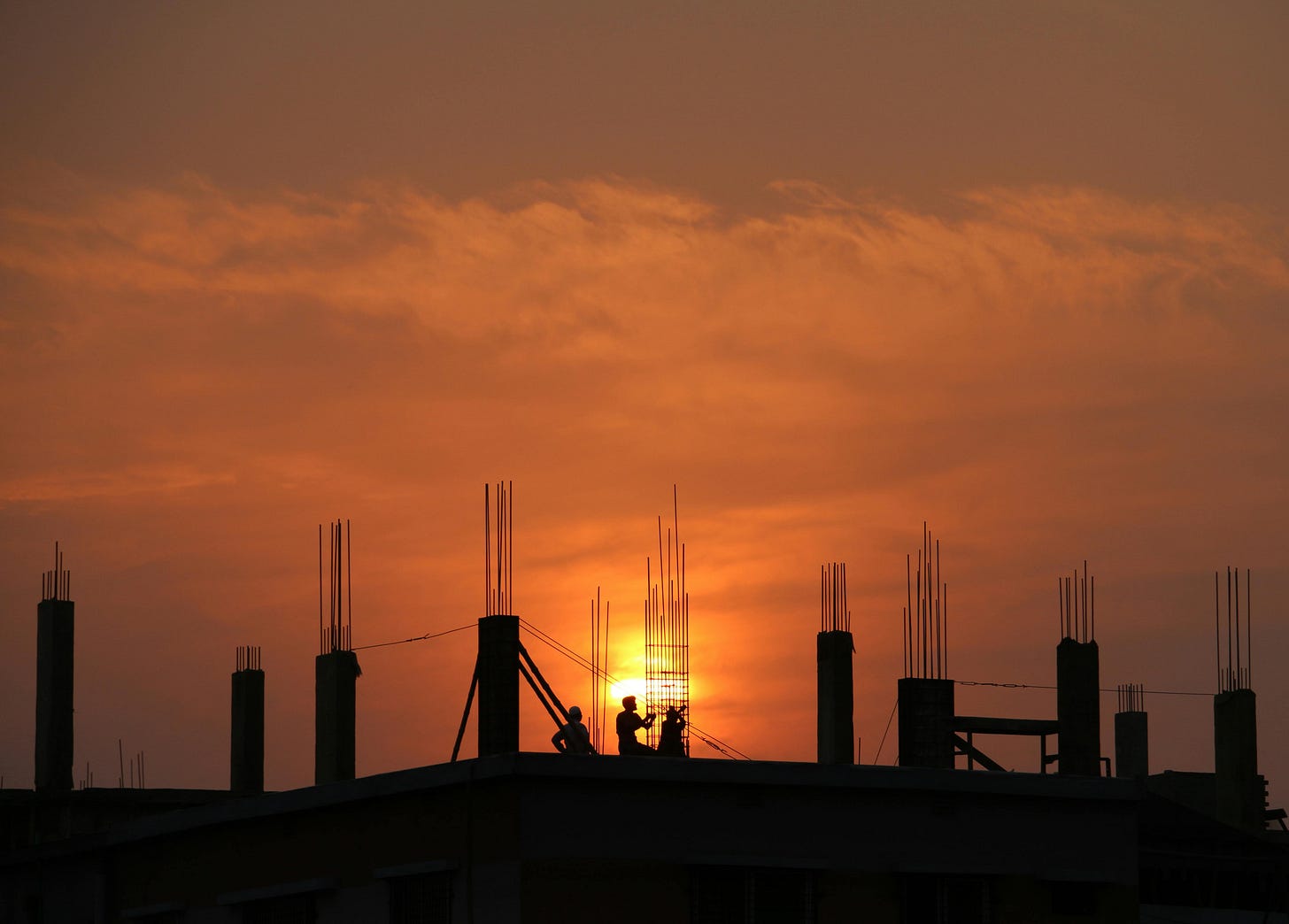 Silhouette of a building under construction in front of a sunset Silhouette of a building under construction in front of a sunset