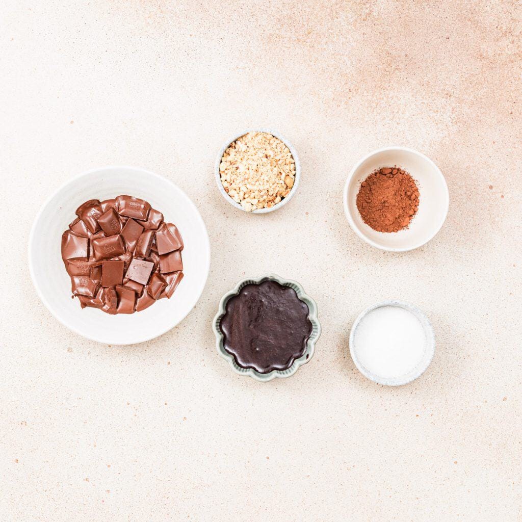 Chocolate, Nutella, cocoa, crushed hazelnuts, and sugar in bowls on textured surface,