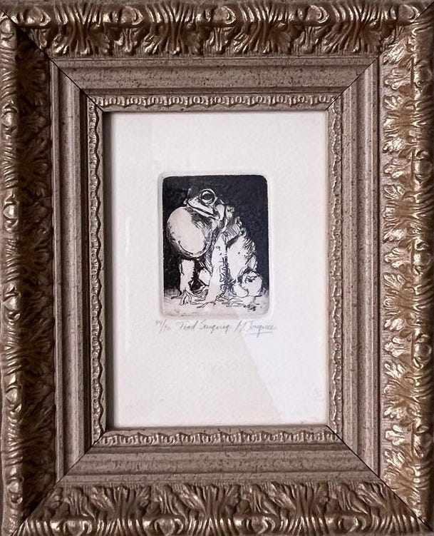 May include: A framed black and white etching of a frog holding a large, round object. The etching is titled 'The Toad Carrying a Jug' and is signed by the artist. May include: A framed black and white etching of a frog holding a large, round object. The etching is titled 'The Toad Carrying a Jug' and is signed by the artist.
