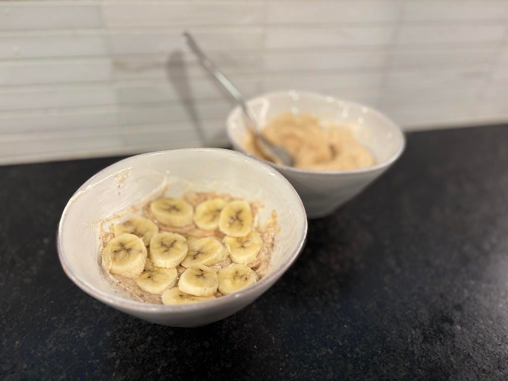Yoghurt mix with almond butter and banana. A second bowl with peanut butter in the back.