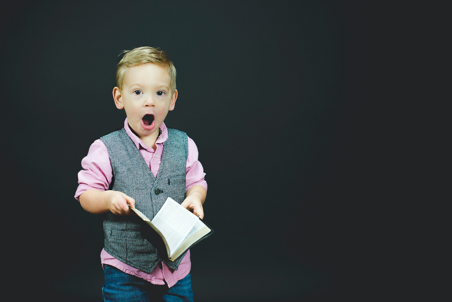 Little boy with book looking surprised