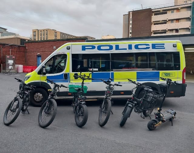 5 e-bikes and 1 e-scooter are lined up in front of a police van.