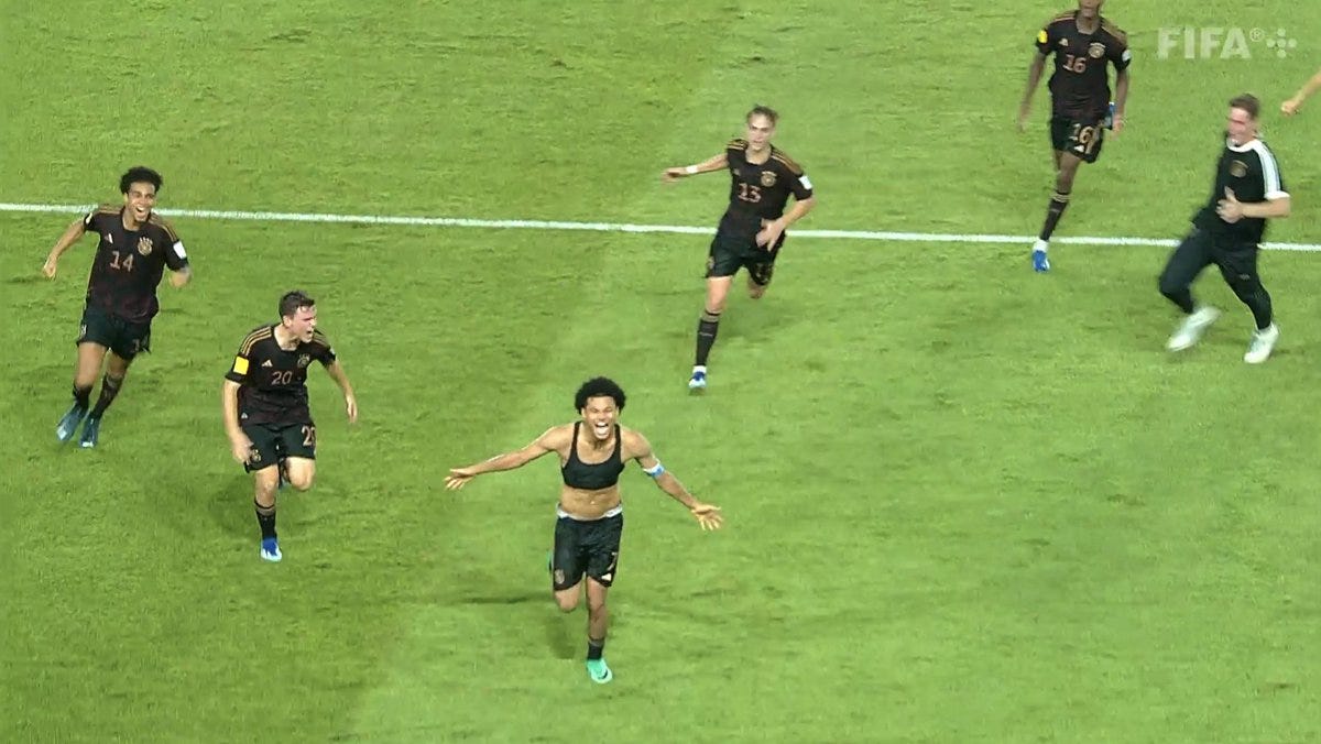 A screenshot of Germany celebrating reaching the FIFA U-17 World Cup final.

Paris Brunner is running with his arms out and shirt off as his team-mates chase him. 