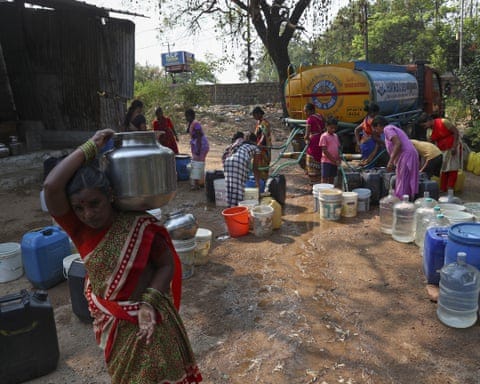 A woman carrying a water vessel after collecting from a tanker