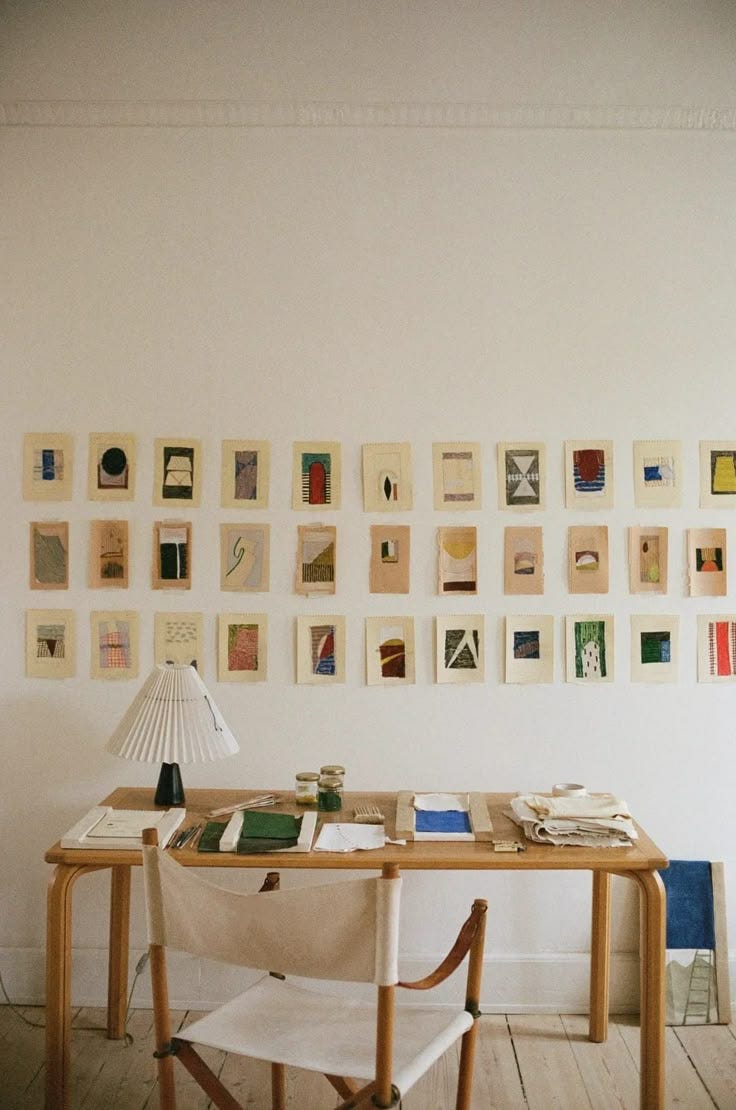This may contain: a desk with a lamp and some pictures on the wall