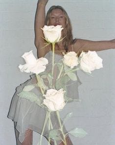 This may contain: a woman is posing with white roses in her hand and arms up to the side