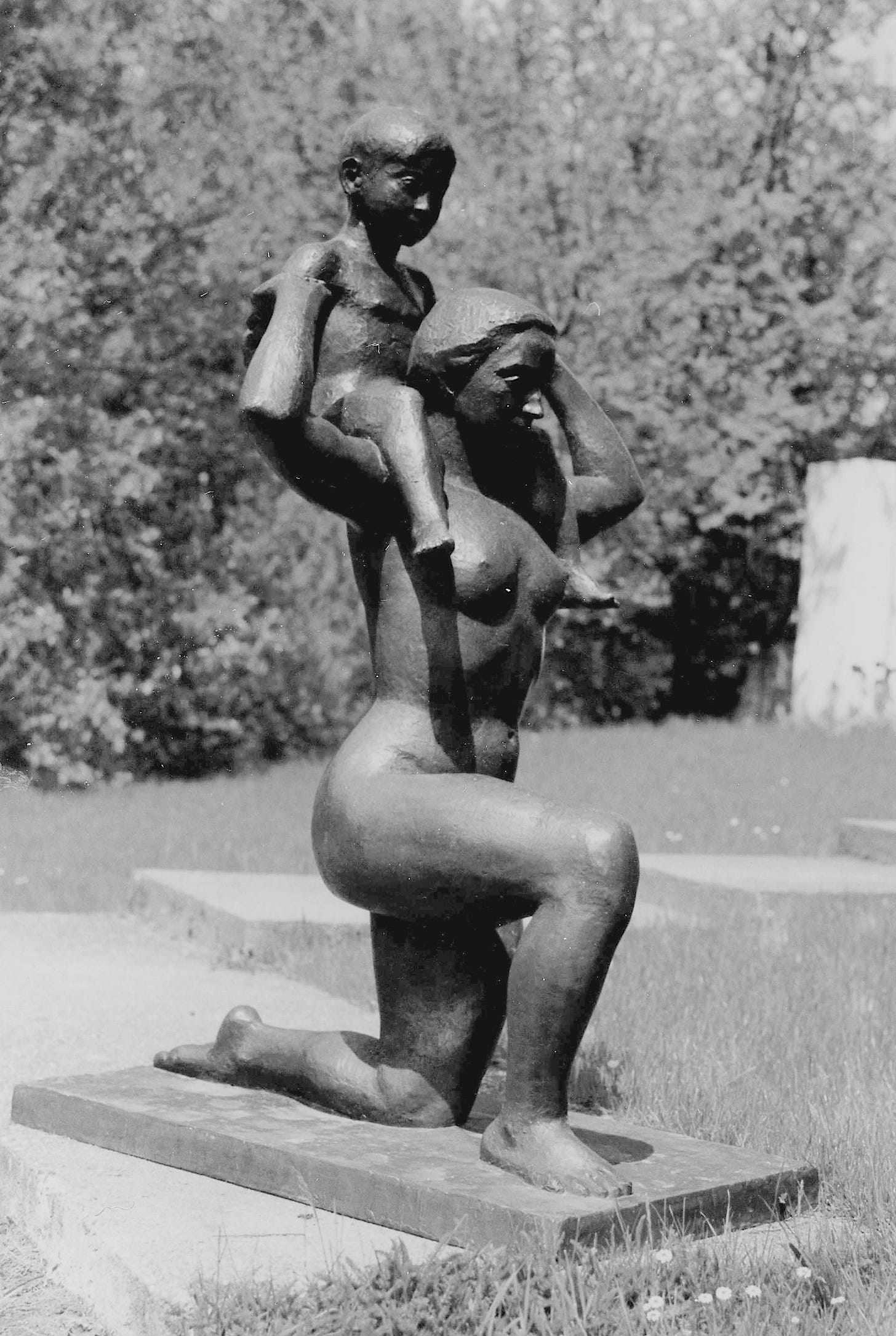 A naked mother kneeling and cradling her naked baby A naked mother kneeling and cradling her naked baby