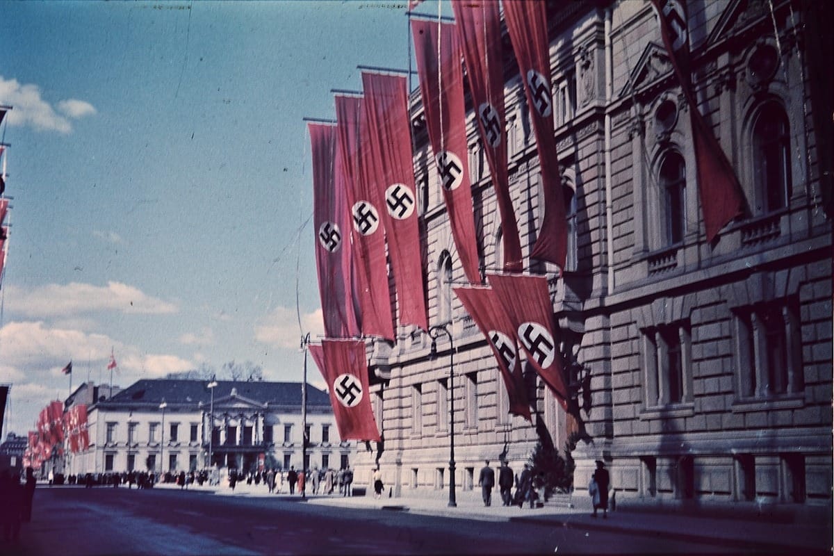 A street in Nazi Germany, where government buildings are adorned with large swastika-bearing flags of the Third Reich