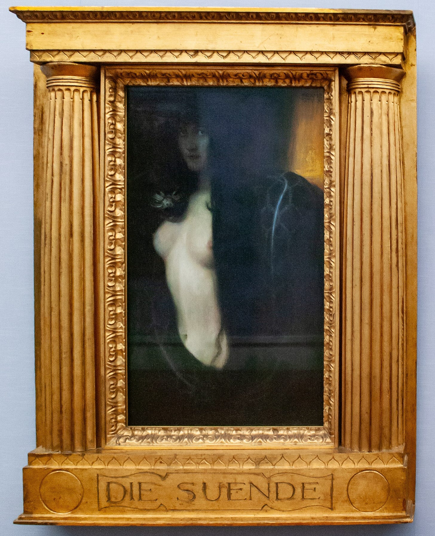 The painting inside a gilded frame shaped like a small temple front, with a half column on each side and the title carved in the base.