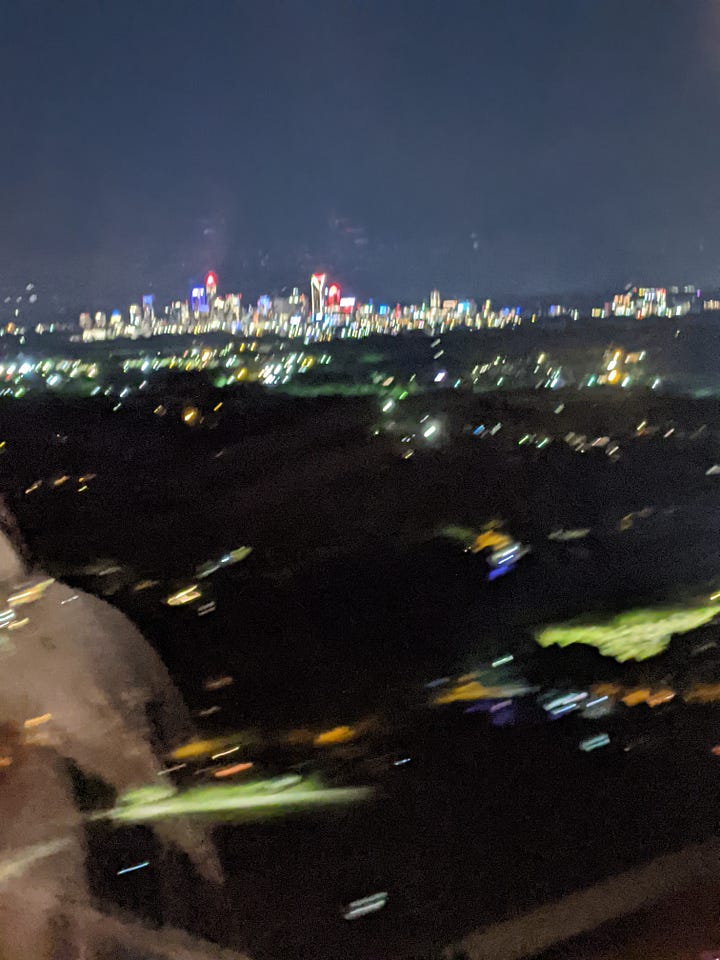 Two mirror photos of me, wearing green and blue in each one. The Atlantic Ocean at Virginia Beach, and Charlotte through the plane window at almost midnight.