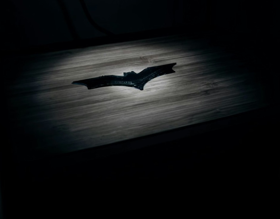 Batman symbol spotlighted on wooden surface