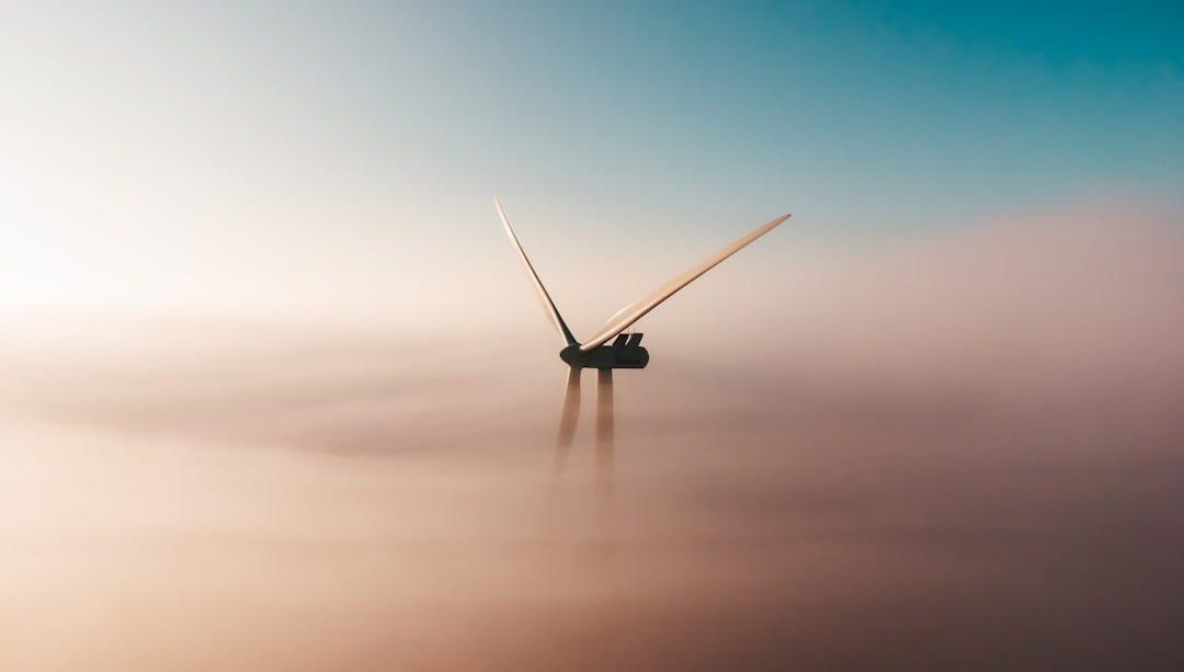 wind turbine emerging from fog at sunrise