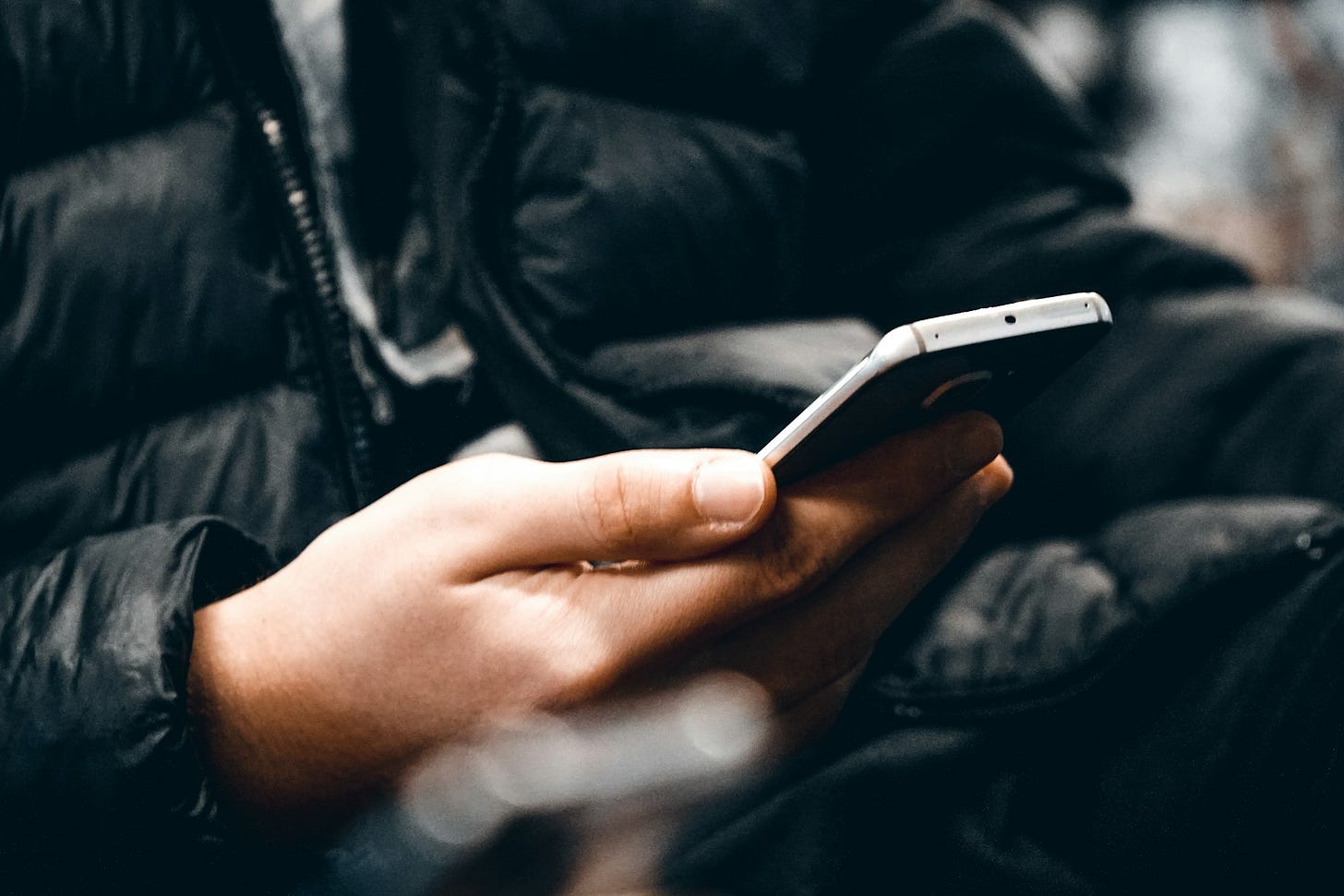 Close-up of a person holding a smartphone while wearing a dark jacket, suggesting a public phone conversation or texting. Photo by Mert Kahveci on Unsplash Close-up of a person holding a smartphone while wearing a dark jacket, suggesting a public phone conversation or texting. Photo by Mert Kahveci on Unsplash